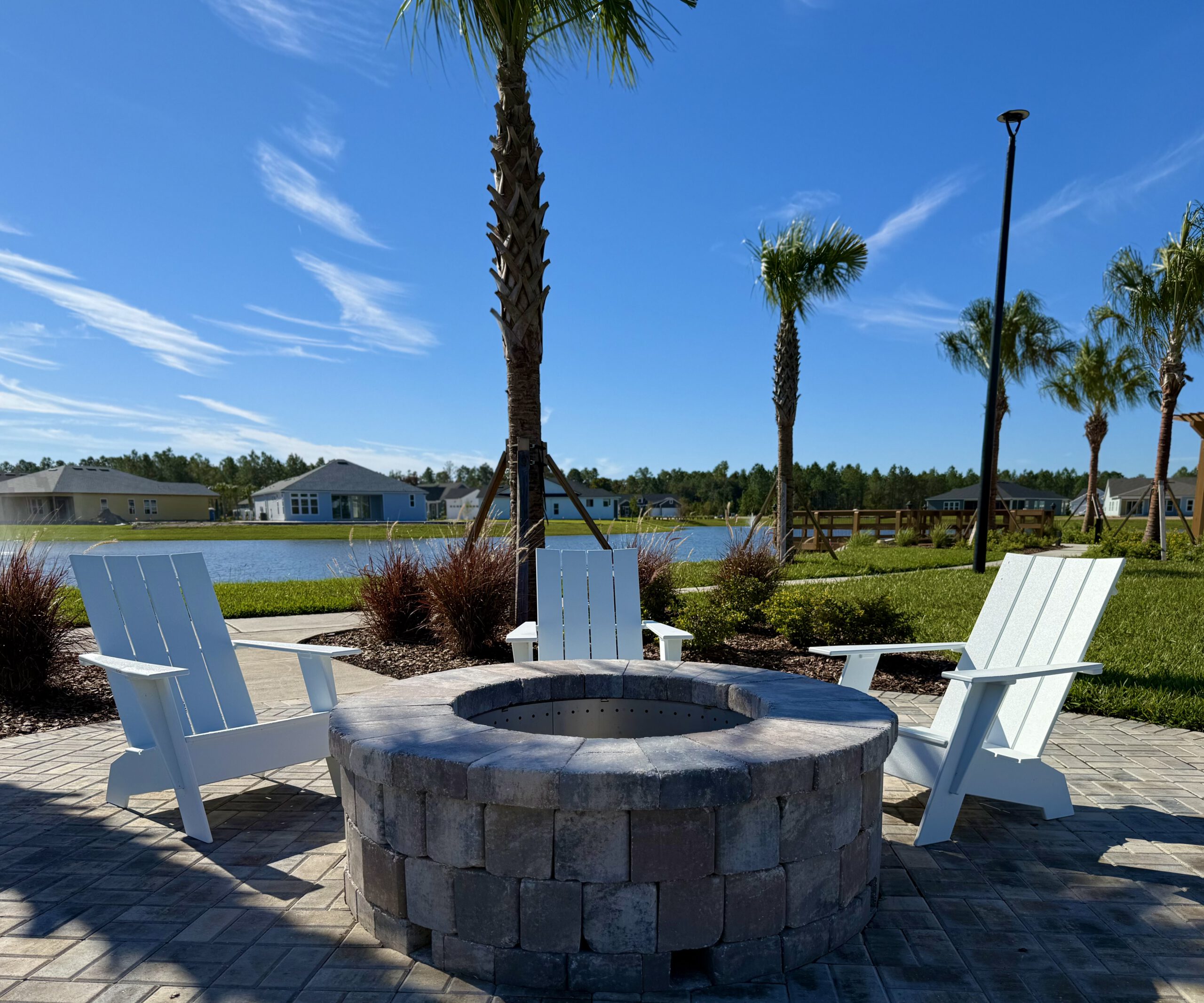 Paver fire pit with Adirondack chairs overlooking a lake