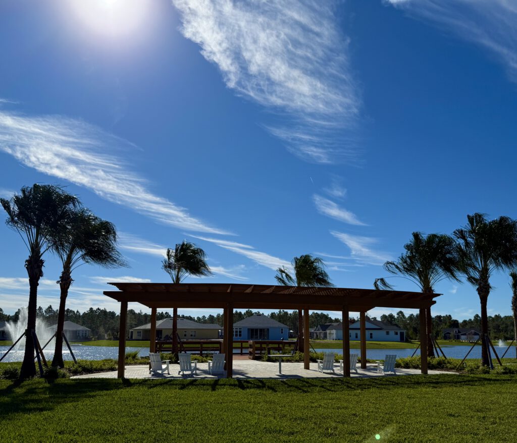 Wood pergola with seating beside a lake with fountains