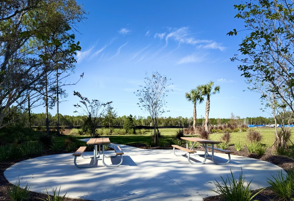 Picnic tables on a concrete pad surrounded by native landscaping