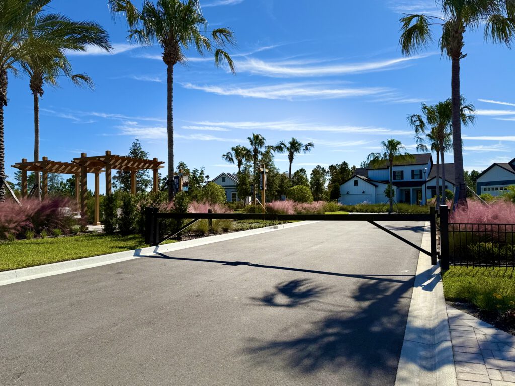 Gated community entrance road with palms and pergola