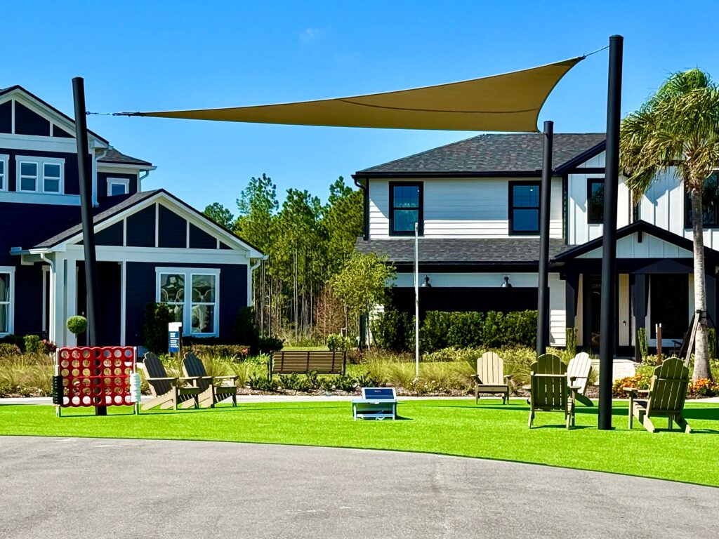 Community lawn with shade sail, lawn games and Adirondack chairs
